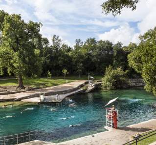People swimming in Barton Springs Pool with lifeguard in stand