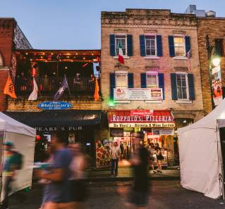 people walking down 6th Street in front of Roppolo's Pizzeria and Shakespeare's Pub in Austin Texas
