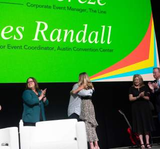 Two people hugging on stage in congratulations on winning a scholarship award.