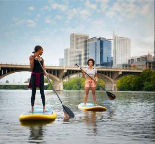 Two Women Stand up paddleboarding on Lady Bird Lake In Austin, TX