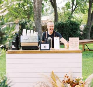 Man standing behind an event bar happily making specialty lattes.
