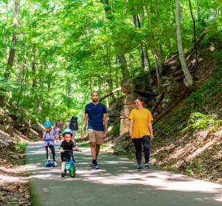 family with children on bikes walk the Clarksville Greenway
