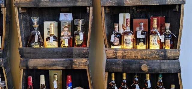 Two tall shelves holding dozens of bottles of vintage bourbon at Revival Vintage Spirits