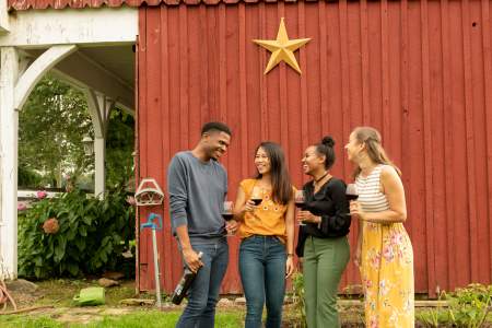 friends enjoying wine in front of red barn