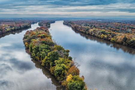 Fall foliage along the Potomac River and a tree-covered island seen from aerial view at Algonkian Regional Park in Sterling