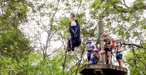 Young man ziplining through trees