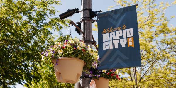 Colorful flowers hanging on a flag pole with welcome sign in downtown rapid city, sd