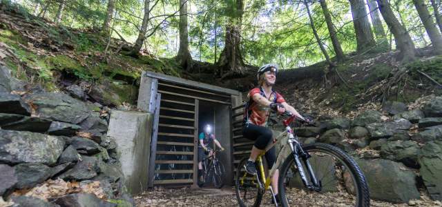 Two bikers ride through mine opening.