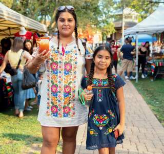 Two girls in braids and colorful dress at a festival
