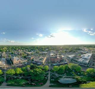 Drone photograph of the City with the sun peaking in the background on a blue sky day