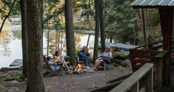 Family sitting around a fire at Hide-a-way Waterfront Cottages
