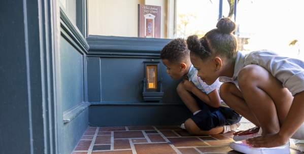 Two children kneeling down to look in a fairy door
