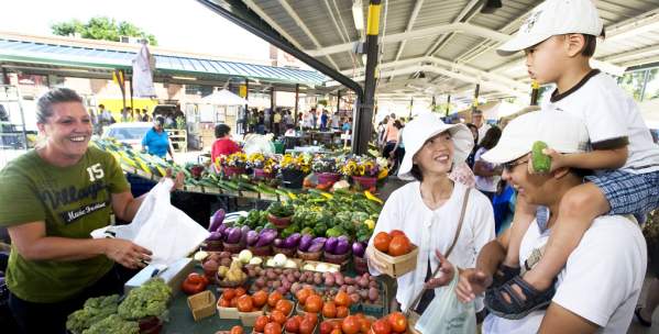 Family buying produce from a woman st the Ann Arbor Farmers Market