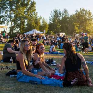 3 friends sitting on the lawn at an Amp Concert