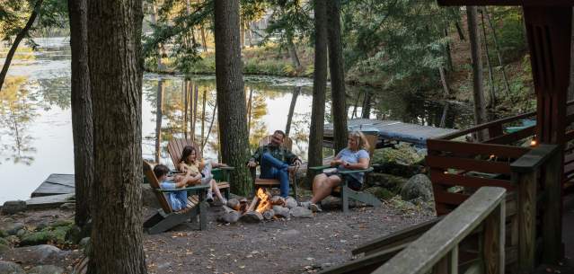 Family sitting around a fire at Hide-a-way Waterfront Cottages
