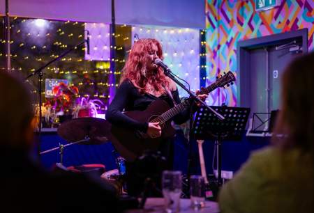 A woman playing an acoustic guitar on a small stage