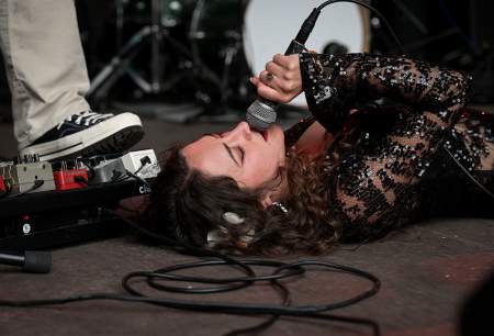 A woman lying on the ground singing into a microphone