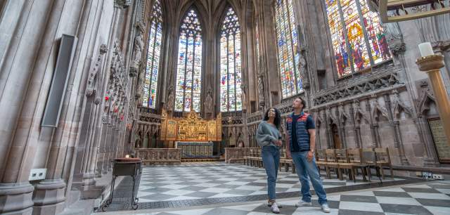 man and woman inside Lichfield Cathedral admiring the Herkenrode stained glass windows.