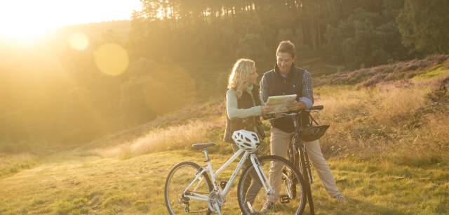 Cannock Chase heathland Autumn sunshine couple on bikes stopping to read map