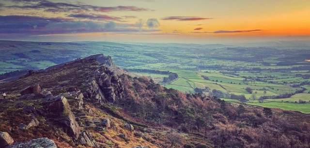 Gritstone rocky ridge known as the Roaches with view across open countryside at sunset