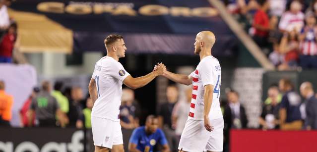 Two soccer players shaking hands on a soccer field.