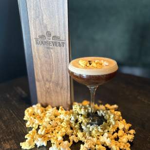 Espresso martini garnished with popcorn and coffee beans, surrounded by popcorn at The Roosevelt Room.