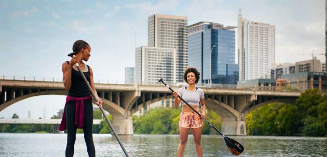 Two Women Stand up paddleboarding on Lady Bird Lake In Austin, TX