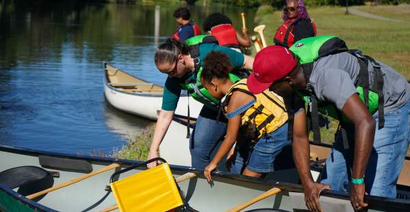 A family puts their canoe in the water before getting in to paddle.