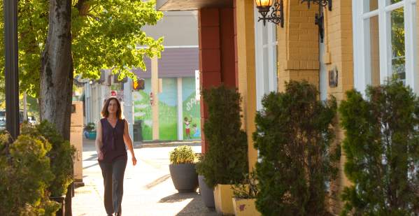 A woman in warm weather walking down Main Street in Springfield by the yellow Washburne Cafe.