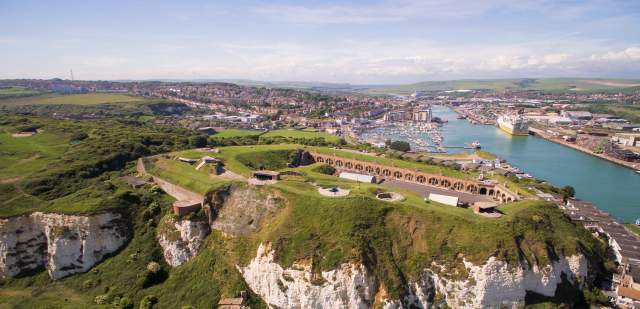 Aerial view of the grounds and red brick buildings of Newhaven Fort with sea in the distance