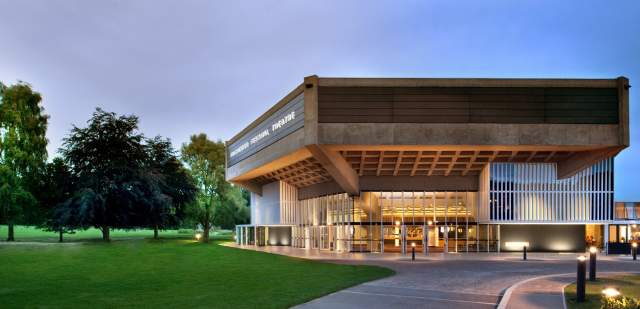 Exterior of the square roof of Chichester Festival Theatre building lit up at night