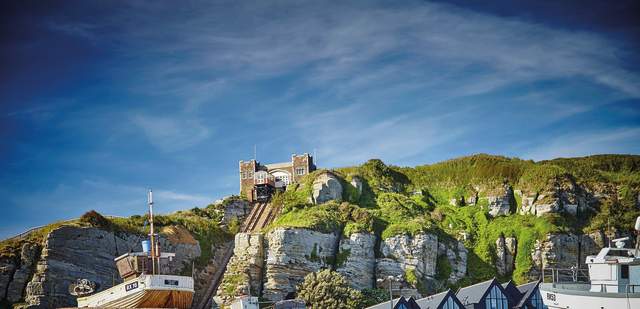 Shingle beach and fishing boat in Hastings Old Town, with cliffside lift in the background