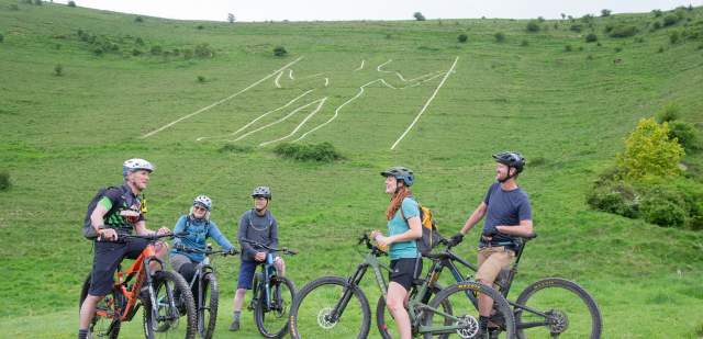 A group of cyclists from Marmalade MTB sit in front of the Long Man of Wilmington in East Sussex