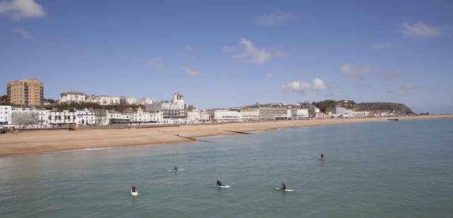 Group of paddleboarders on the sea with Hastings and beach in the backgroud