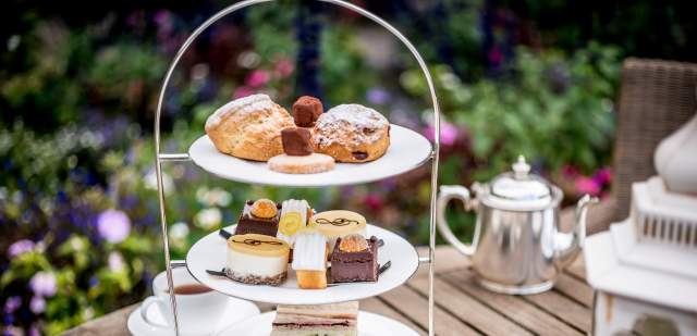 Three tiered afternoon tea selection of cakes, sandwiches and a tea pot at Amberley Castle