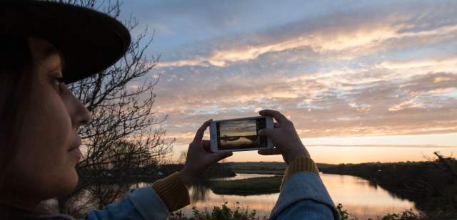 A solo traveller taking a photo of sunset in the Seven Sisters country Park