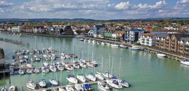 Yachts moored on the river at Littlehampton harbour, with riverside apartments on the opposite side