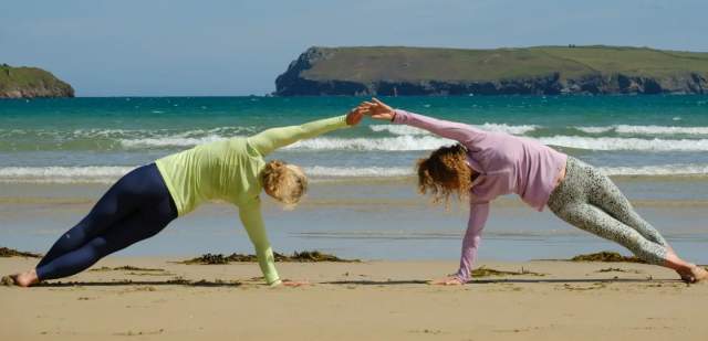 Two people doing yoga on the sandy beach at the Witterings