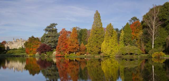 Sheffield Park house in distance with autumnal trees alongside the lake