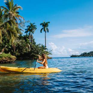 Woman kayaking in a sunny day. At the background you can see palm tree on the Solarte island