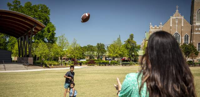 Family playing football on Bell Tower Green
