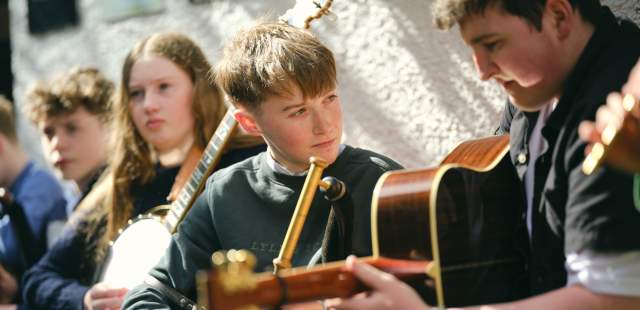 Piper and guitar player sitting side by side performing