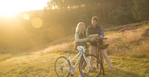 Cannock Chase heathland Autumn sunshine couple on bikes stopping to read map