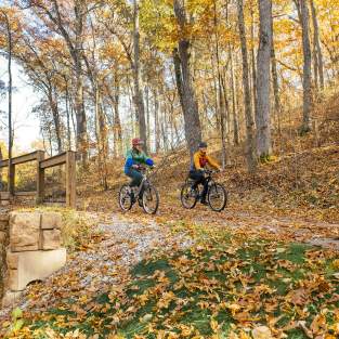 Mother and daughter mountain biking down a path in the fall