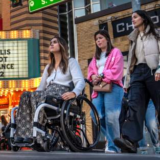 Woman in wheelchair crossing street in front of Michigan Theater