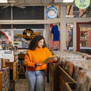 Encore Records- Woman in orange shirt looking at albums in a record store.