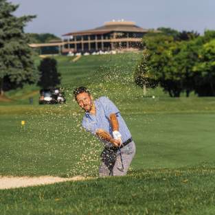 Man hitting golf shot out of sand