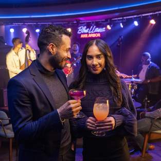 Stylish couple holding drinks at Blue Llama Jazz Club