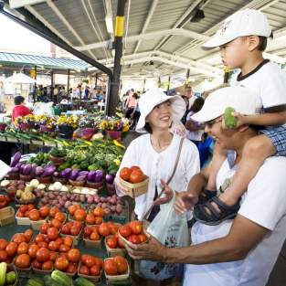 Family buying produce from a woman st the Ann Arbor Farmers Market