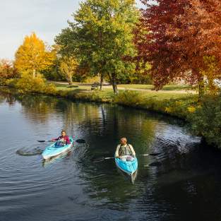 Couple in two kayaks floating on a lake in the fall
